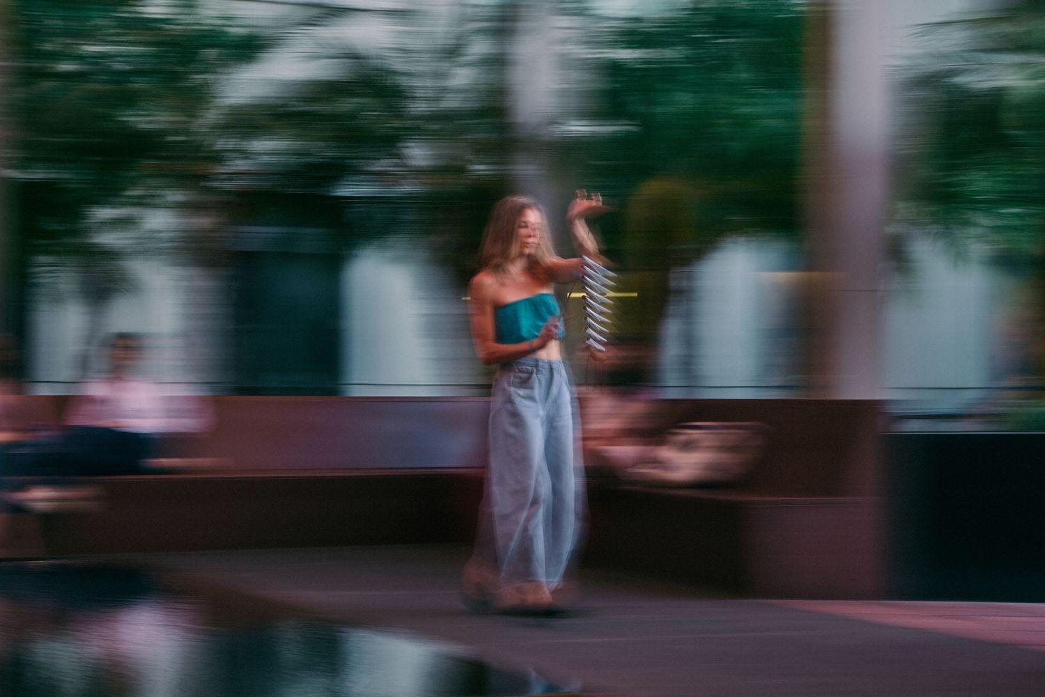 Blurred urban street scene with motion and walking figures.