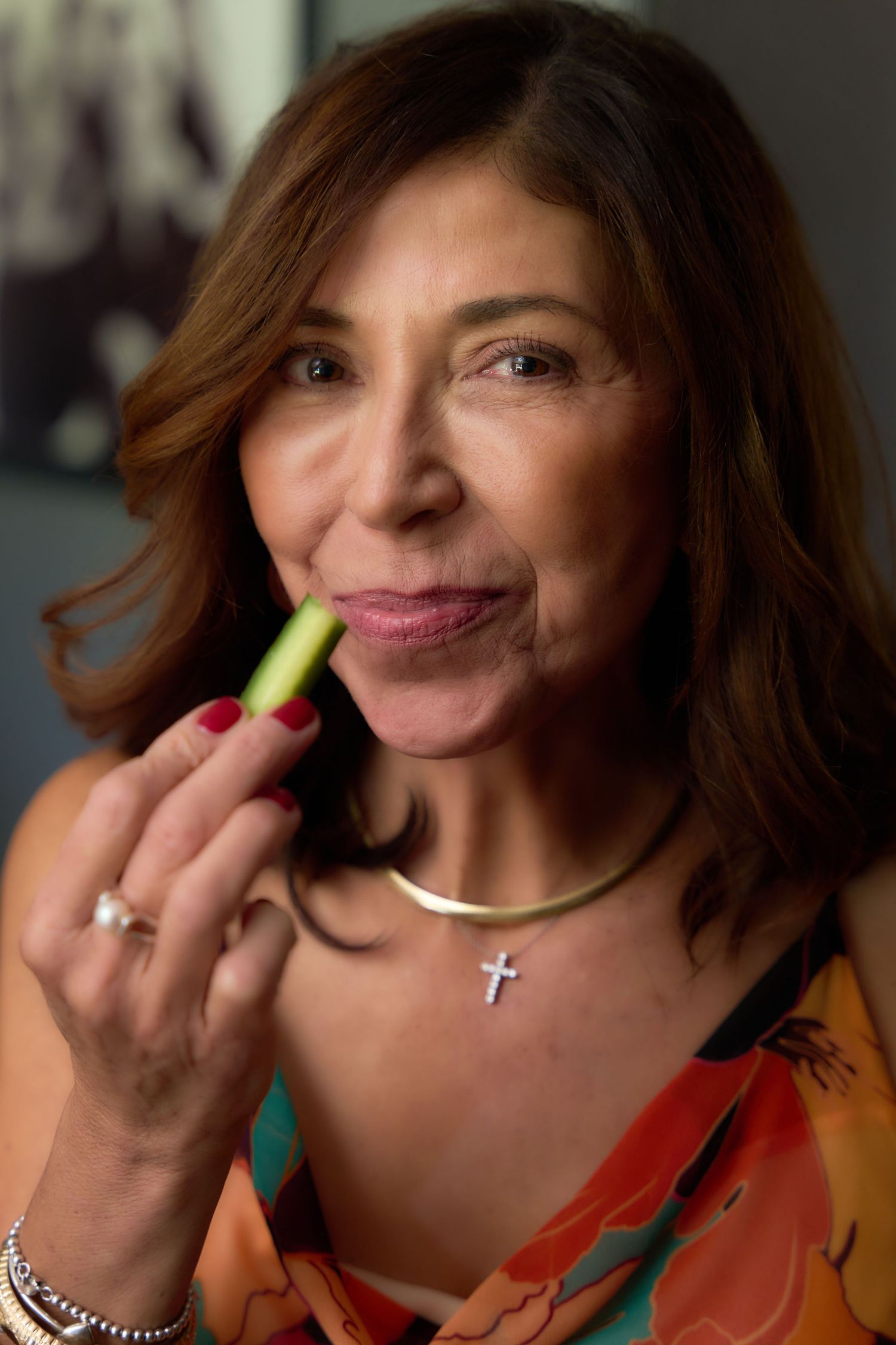 A sequence of five photos showing someone playfully holding a celery stick up to their nose while wearing an orange top.