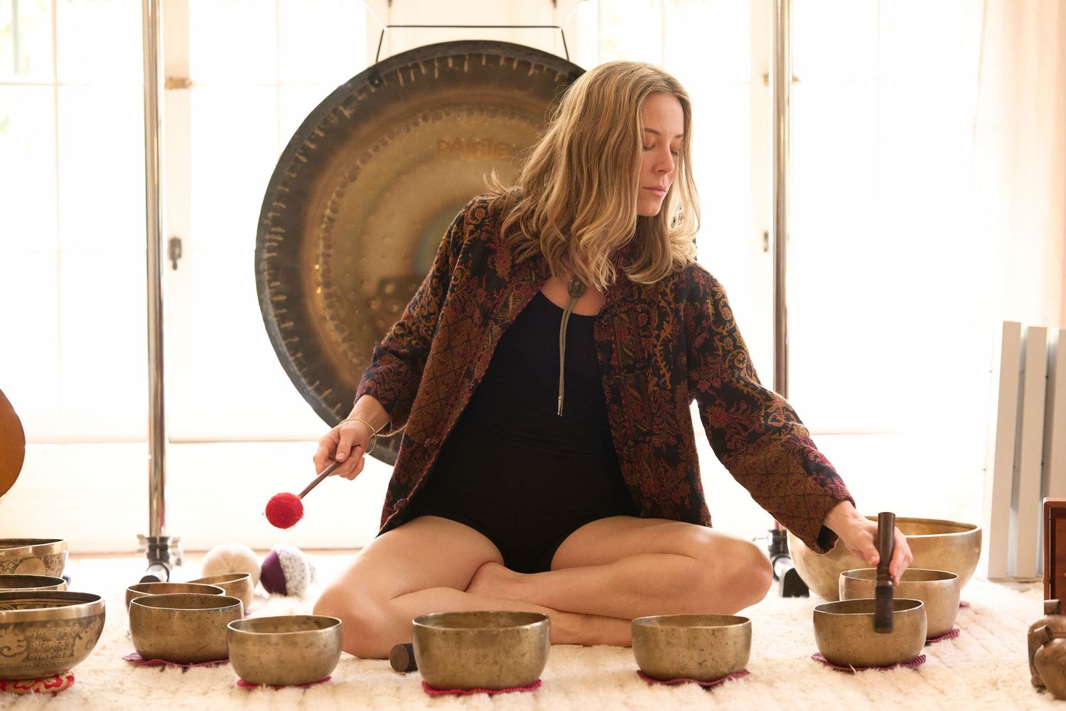 A meditative scene with singing bowls and a large gong in natural lighting.