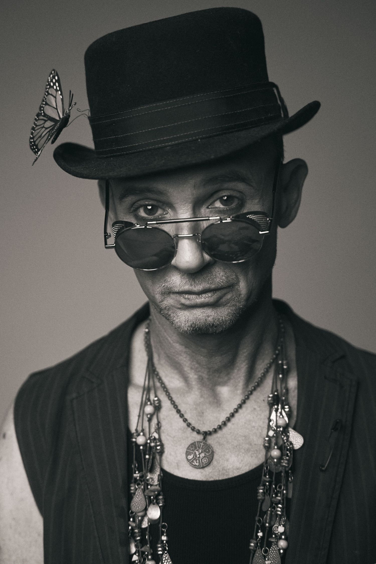 Dramatic black and white portraits featuring someone in a hat with decorative accessories.