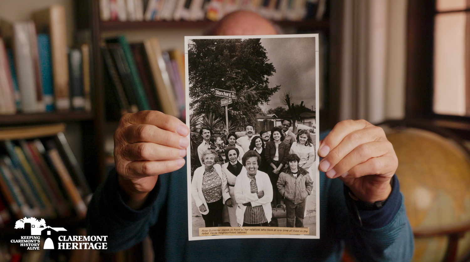 A row of black and white vintage photographs being held and displayed in hands against a wooden surface.