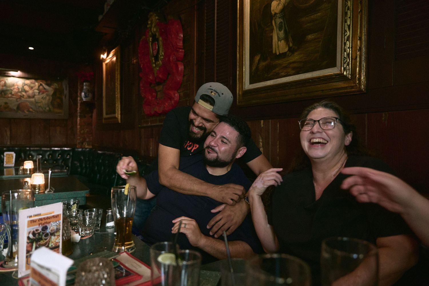 Group of people celebrating with drinks in a dark bar atmosphere.