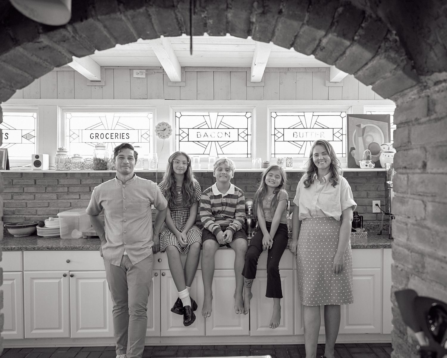 Black and white view of people through arched doorway in retail setting.