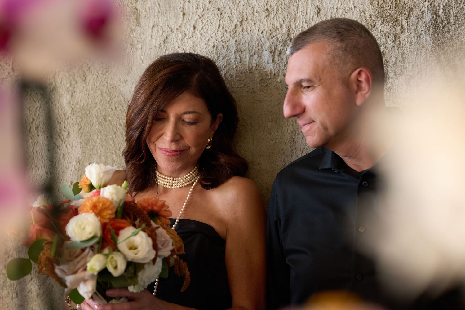 Romantic couple shares intimate moment during wedding reception while sitting at decorated dining table.