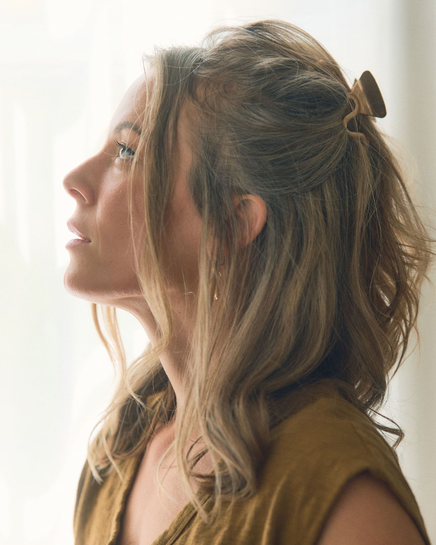 Profile views of woman with wavy hair in soft natural light.