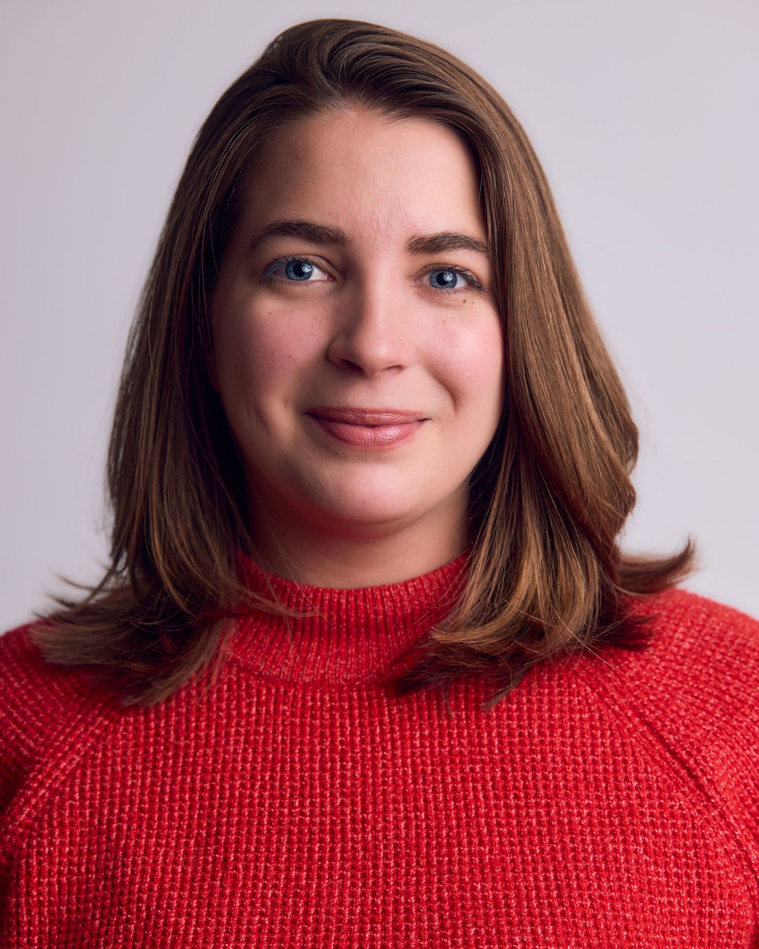 Portrait series showing joyful expressions while wearing a cozy red turtleneck sweater against light background.