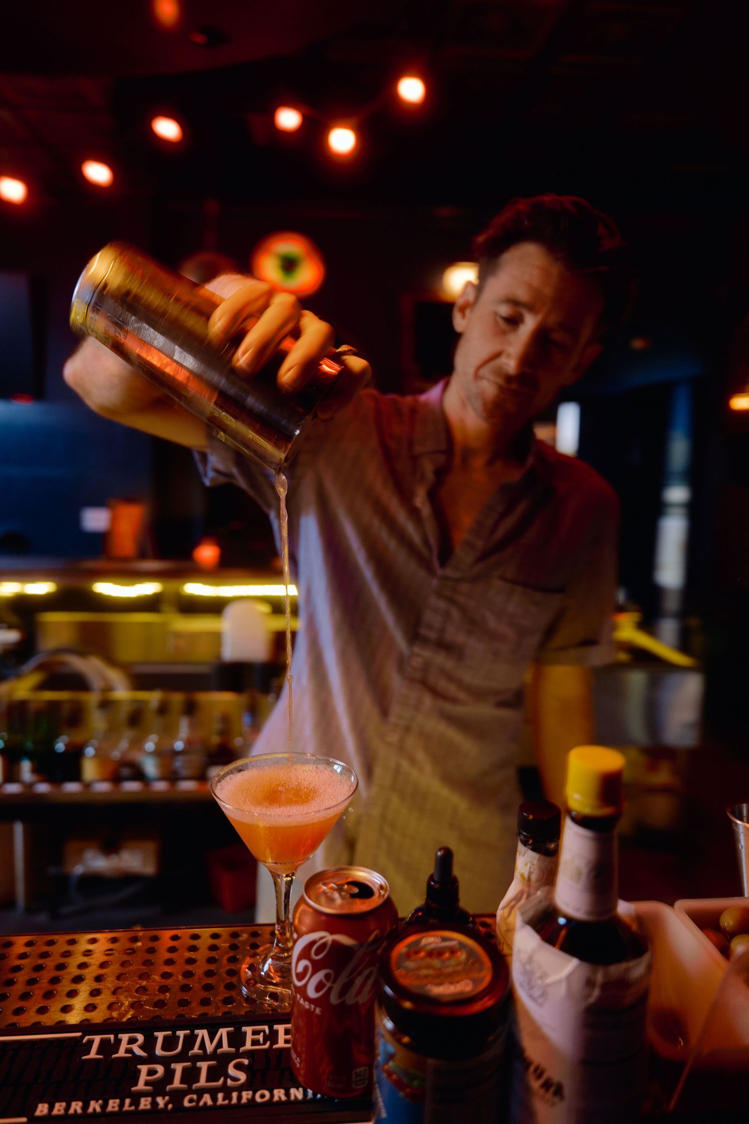 Bartender pouring draft beers at a bar with neon lights in the background.