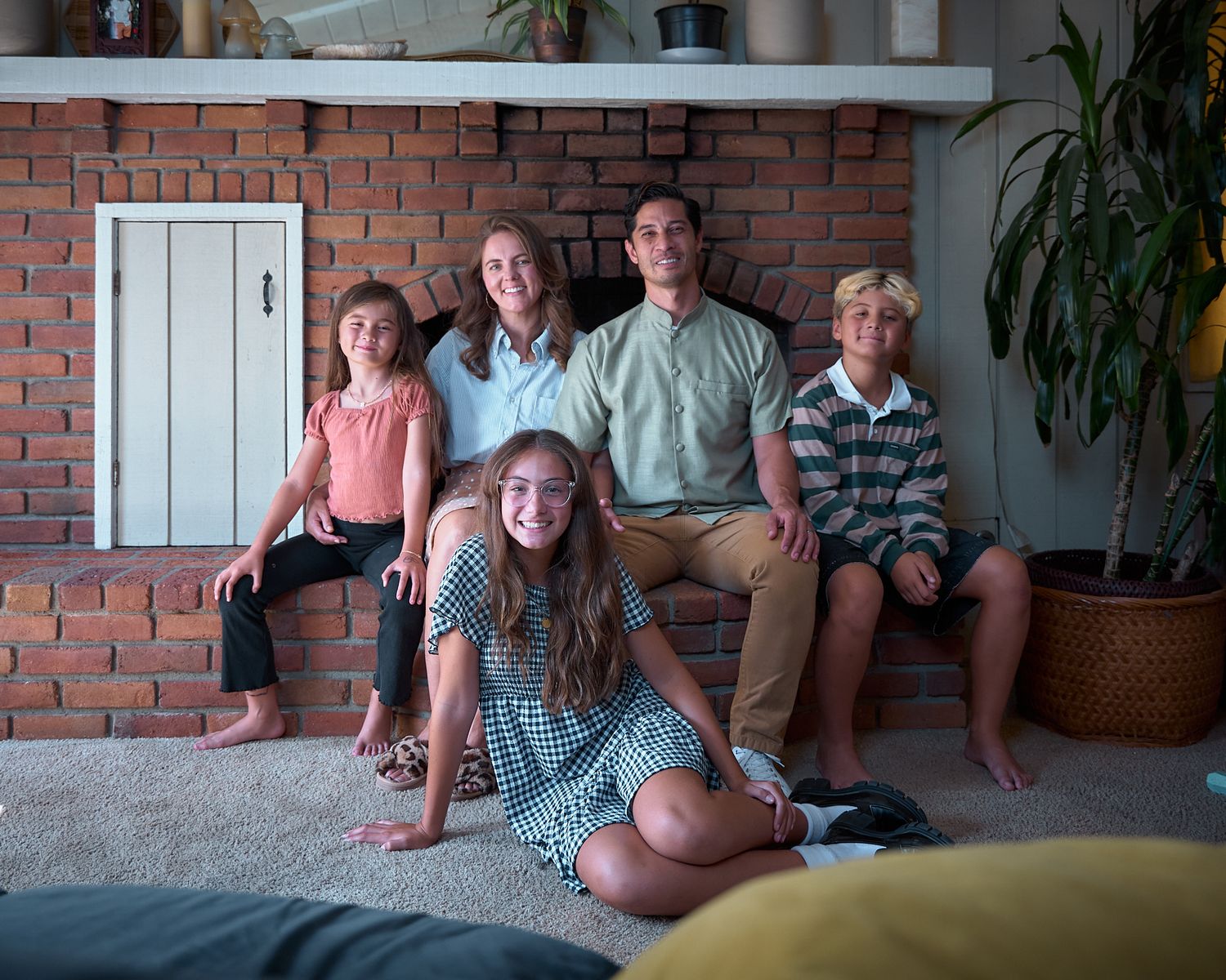 Group enjoying casual conversation in a bright living room with brick walls and plants.