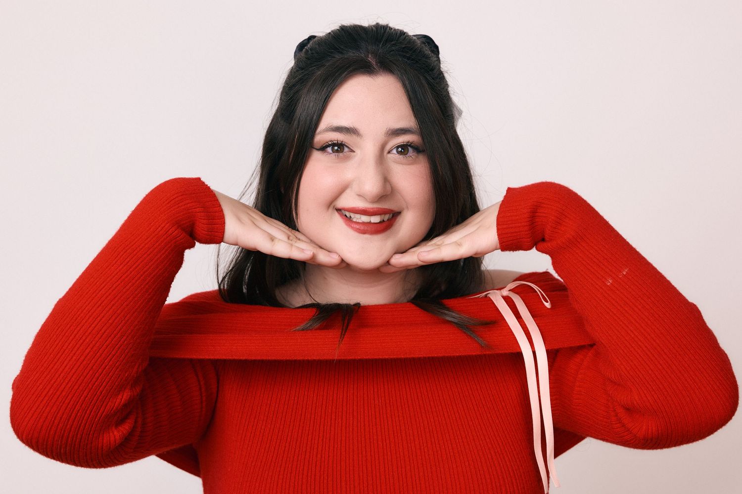Studio portraits in a bright red sweater showing playful expressions.