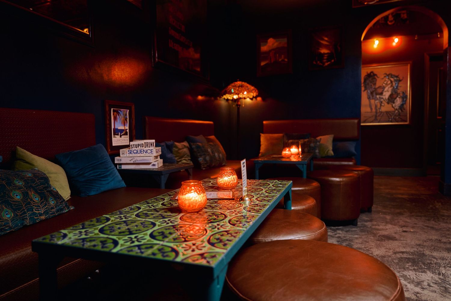 Dark cozy pub interior with illuminated board games and candlelight creating an intimate atmosphere.