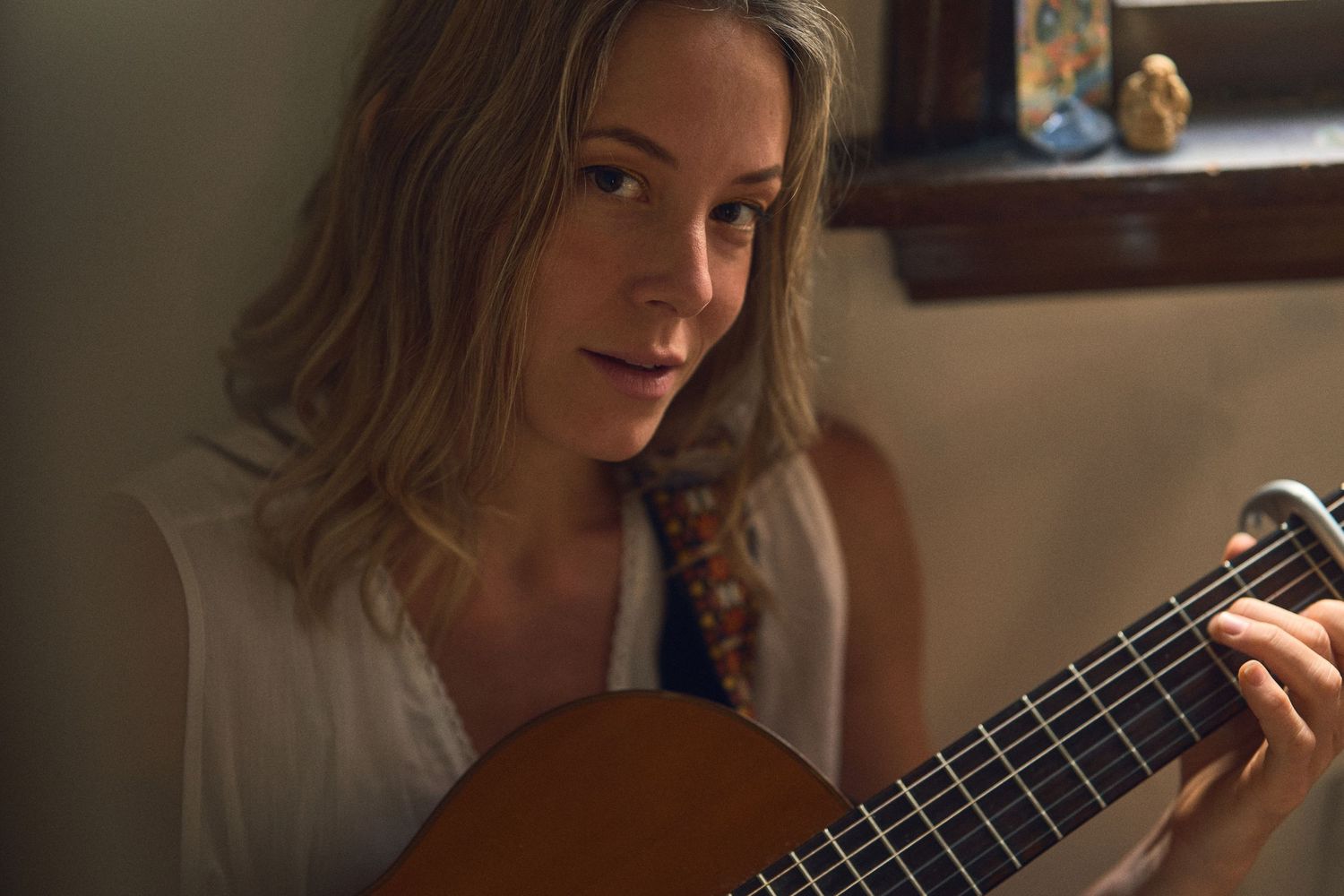Person playing acoustic guitar in gentle indoor lighting.