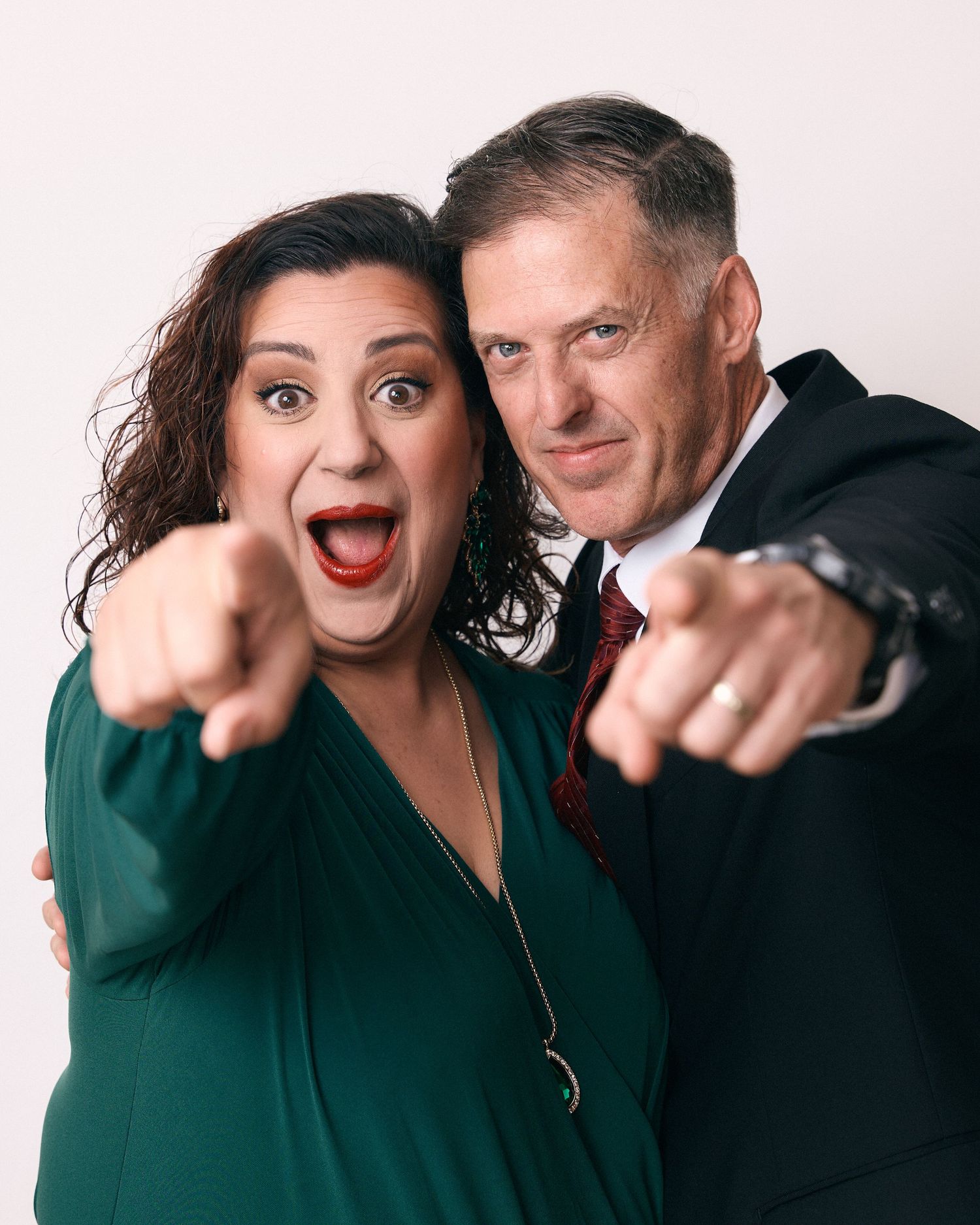 Dynamic studio portraits of two people in green and black pointing playfully at the camera.