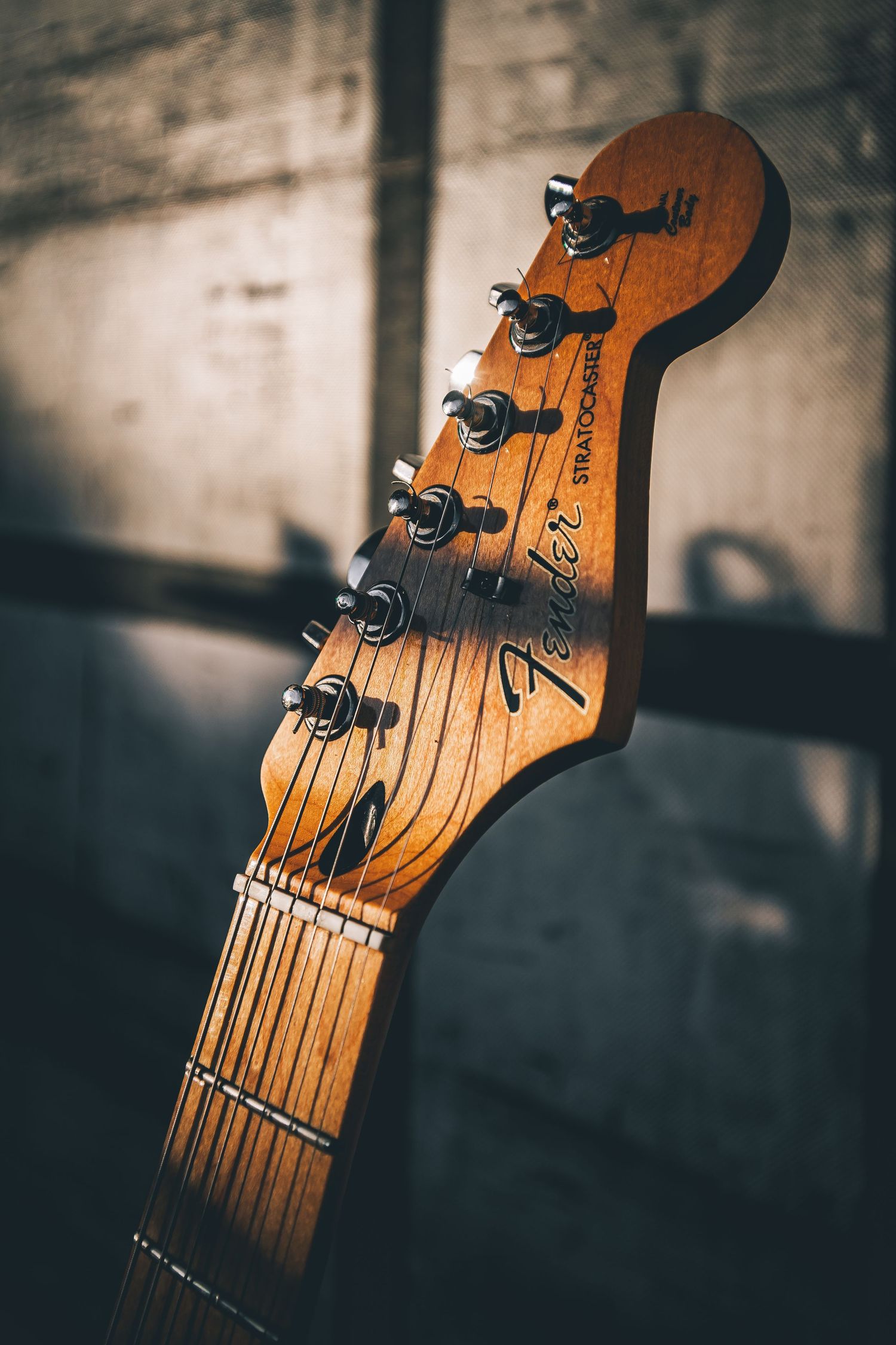 Close-up sequence of a wooden guitar headstock with tuning pegs in warm lighting against a blurred background.