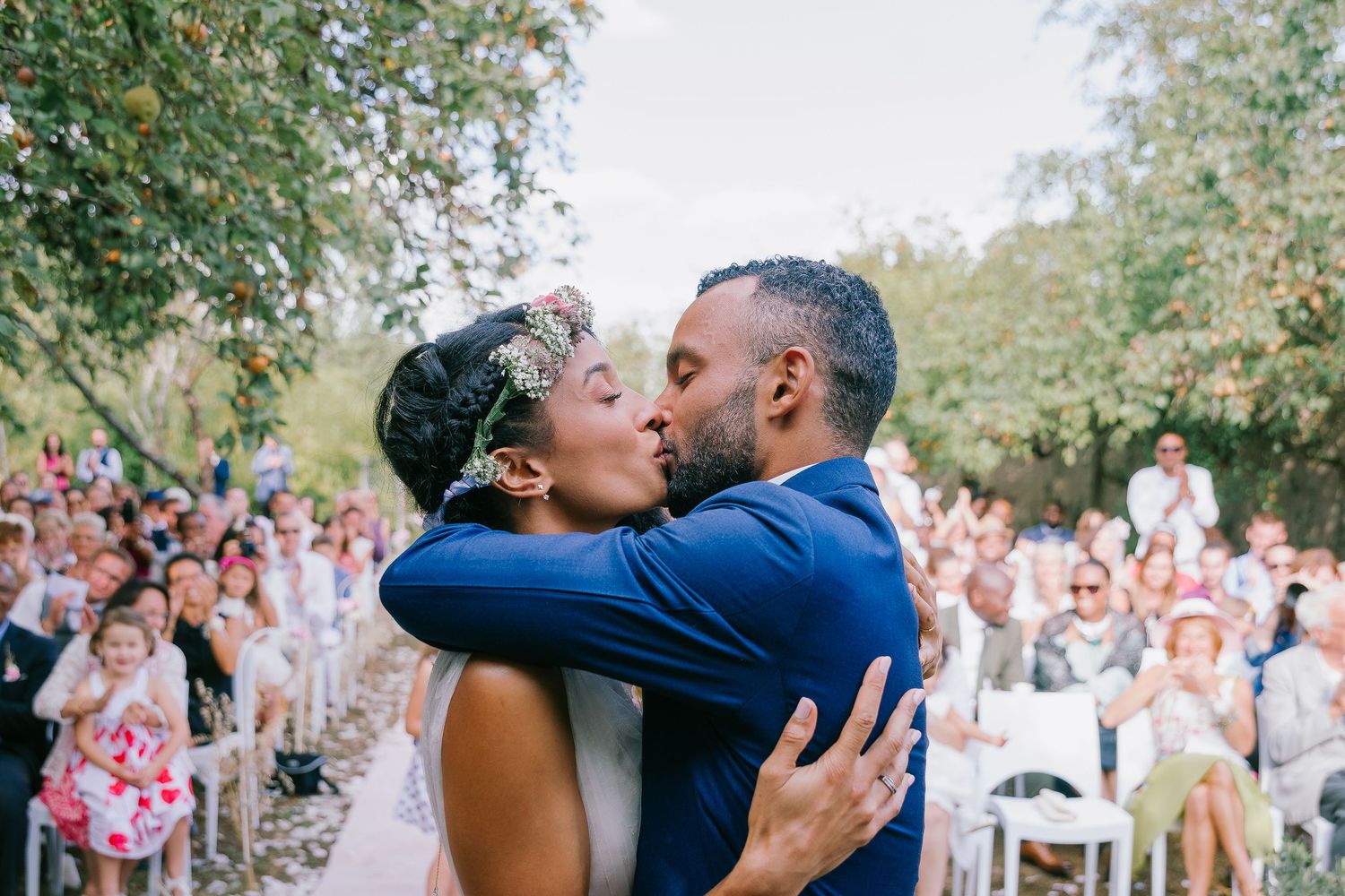 Wedding ceremony kiss captured in a series of joyful moments with guests in background.