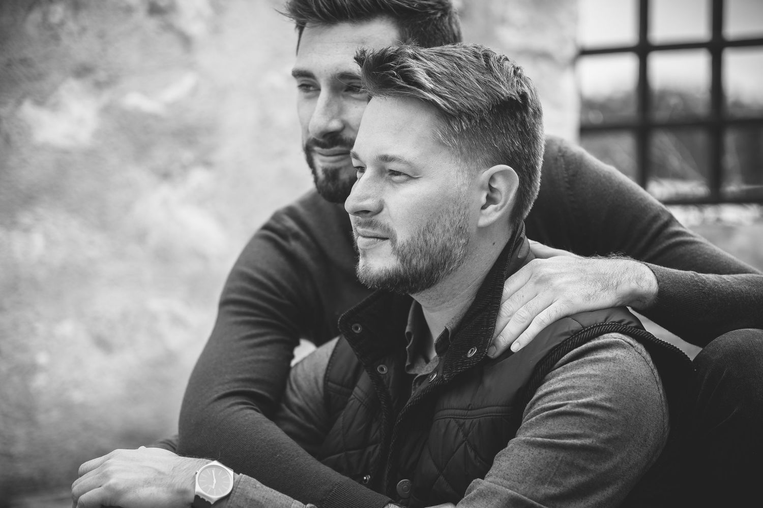 Black and white portrait of two people in casual attire sharing intimate moment.