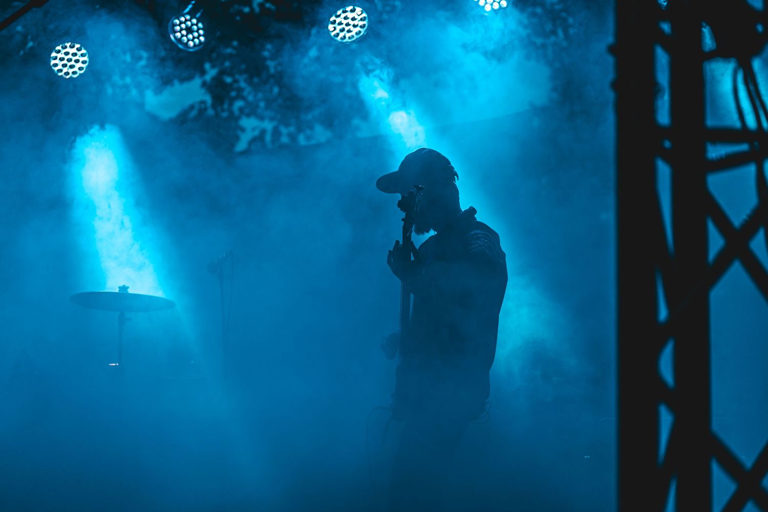 Concert stage illuminated with dramatic blue lighting and fog effects creating an atmospheric performance environment.