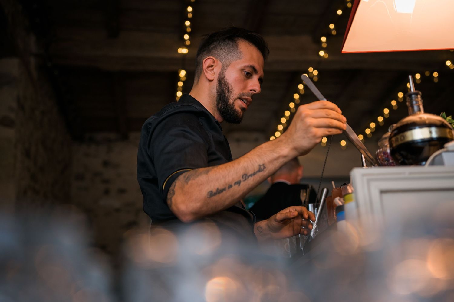Skilled bartender crafting cocktails at dimly lit bar with professional equipment.
