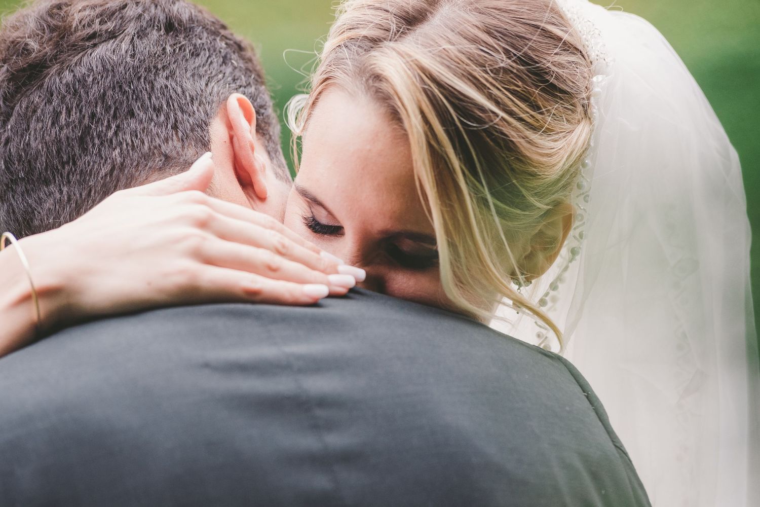 Intimate wedding moment captured as couple embraces with soft natural lighting in outdoor setting.