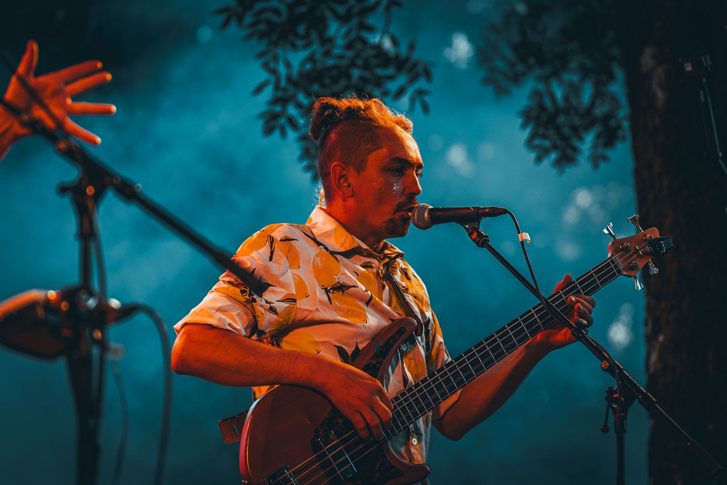 Musicians perform on stage bathed in dramatic blue and red lighting during an energetic concert performance.