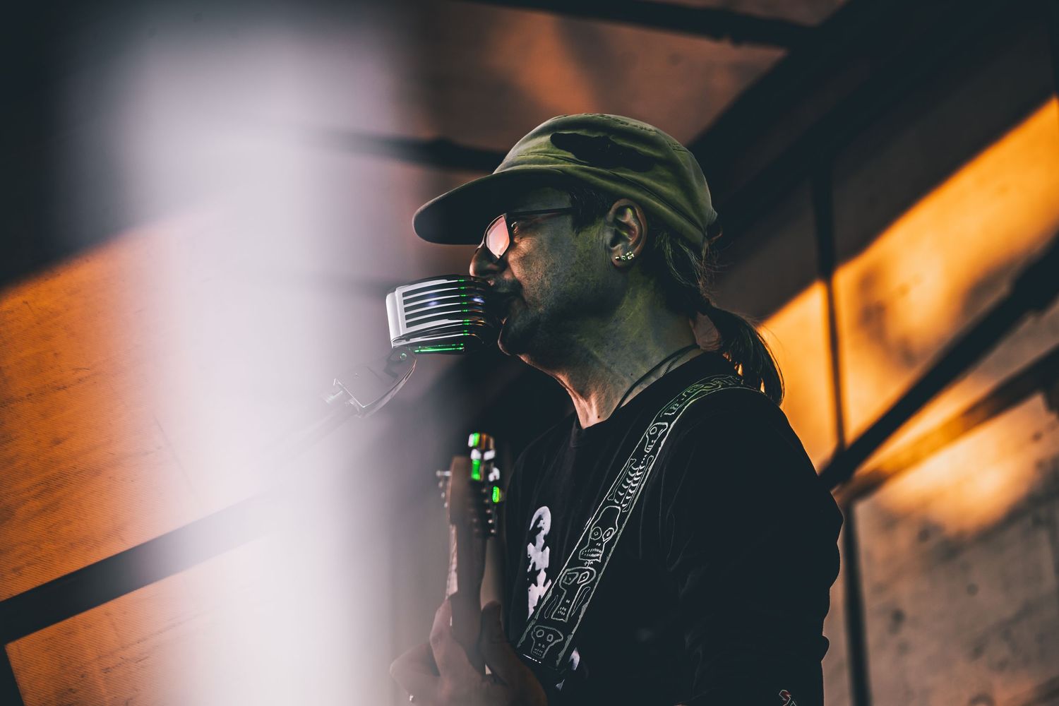 Silhouetted musician performing on stage with microphone and guitar.