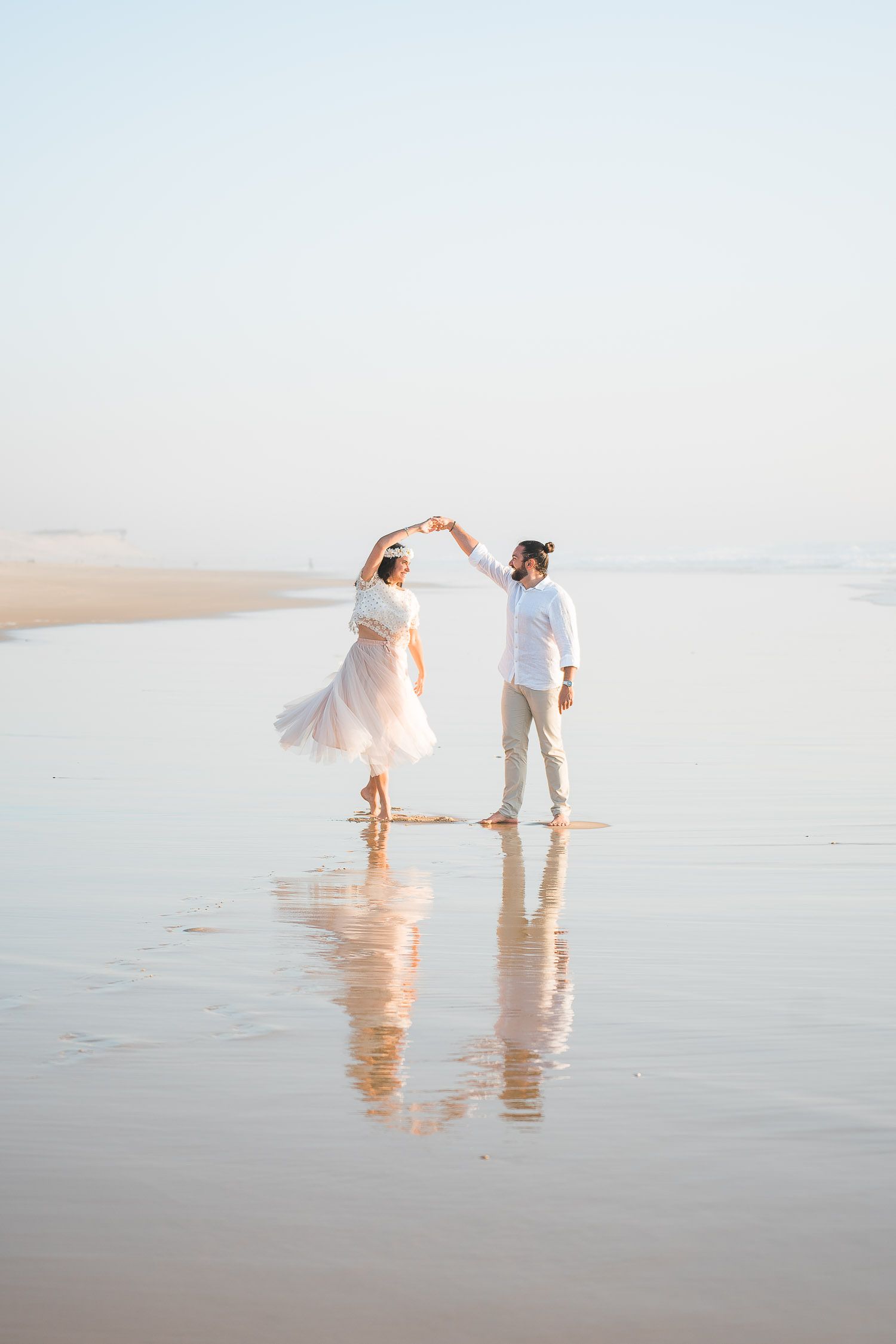 Ethereal beach wedding photos with couple walking on reflective wet sand at sunset.