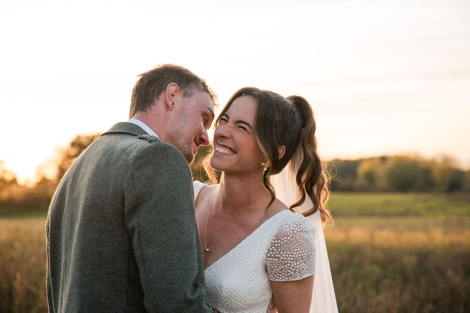 Newlyweds share tender moments during golden hour in an outdoor field setting.