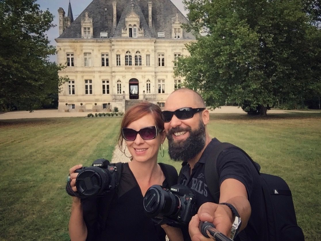 Photographers capturing moments in front of grand chateau during wedding day.