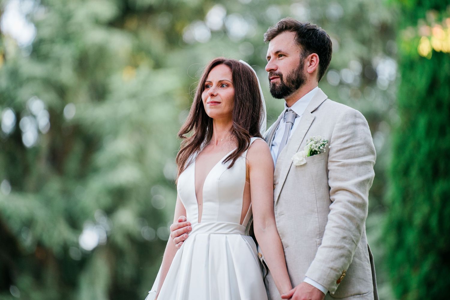 Elegant wedding couple posing in garden setting with natural greenery backdrop.