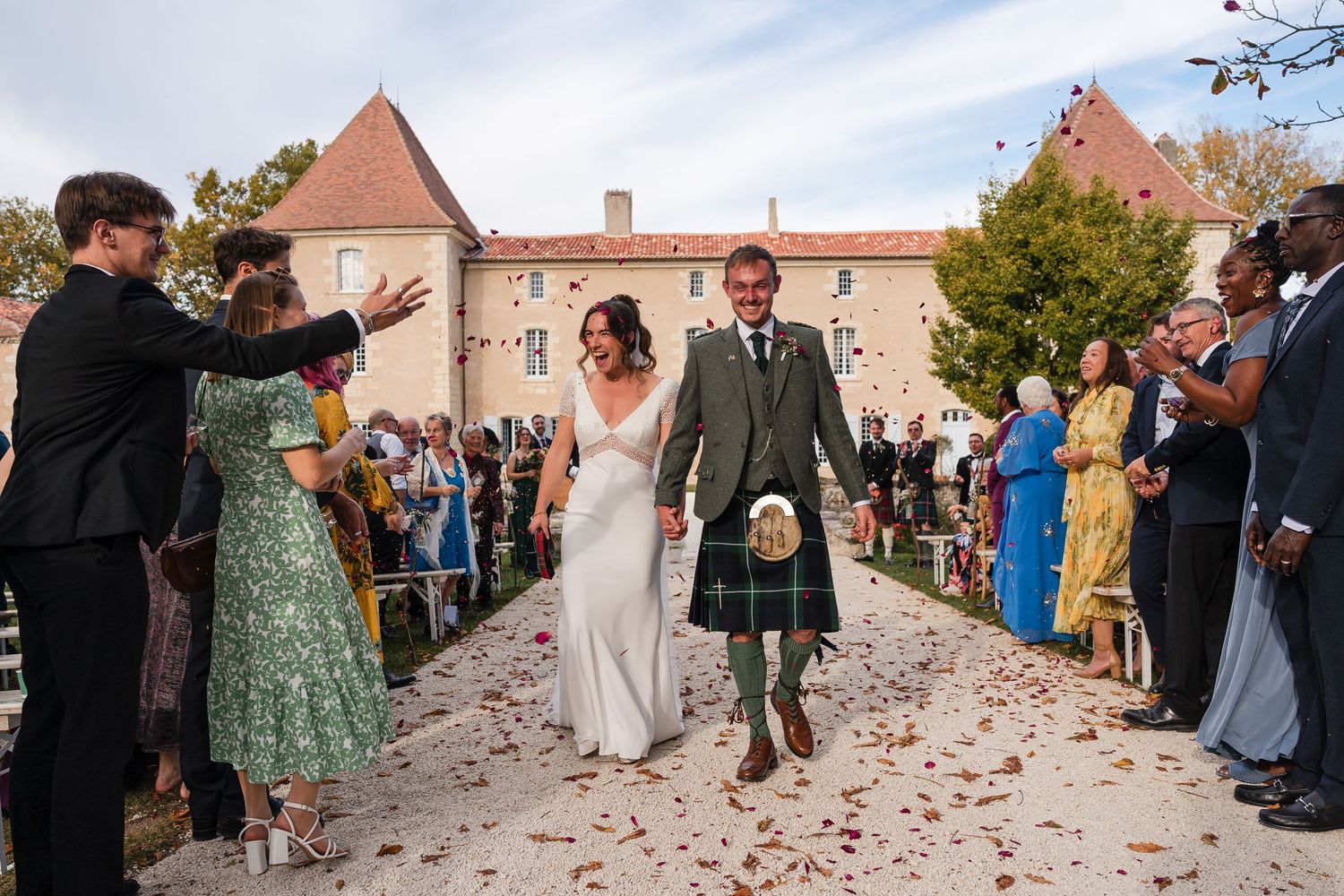 Wedding guests throwing flower petals during an outdoor celebration.
