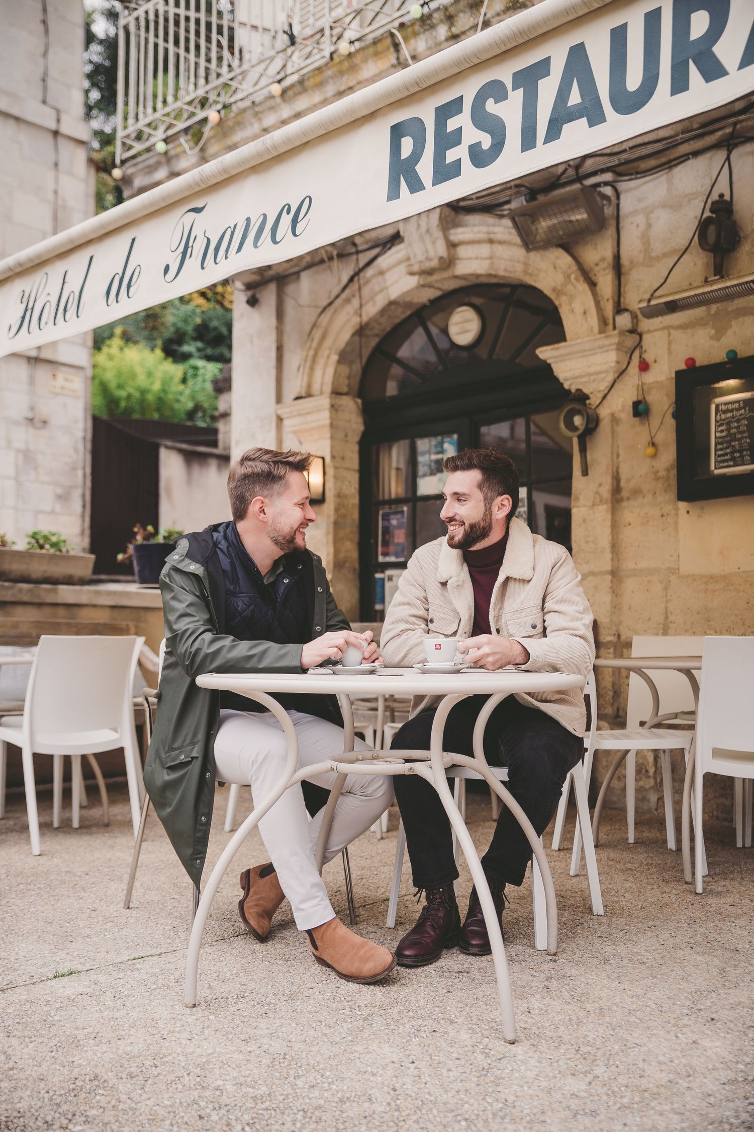 A couple shares intimate moments at an outdoor French restaurant terrace.