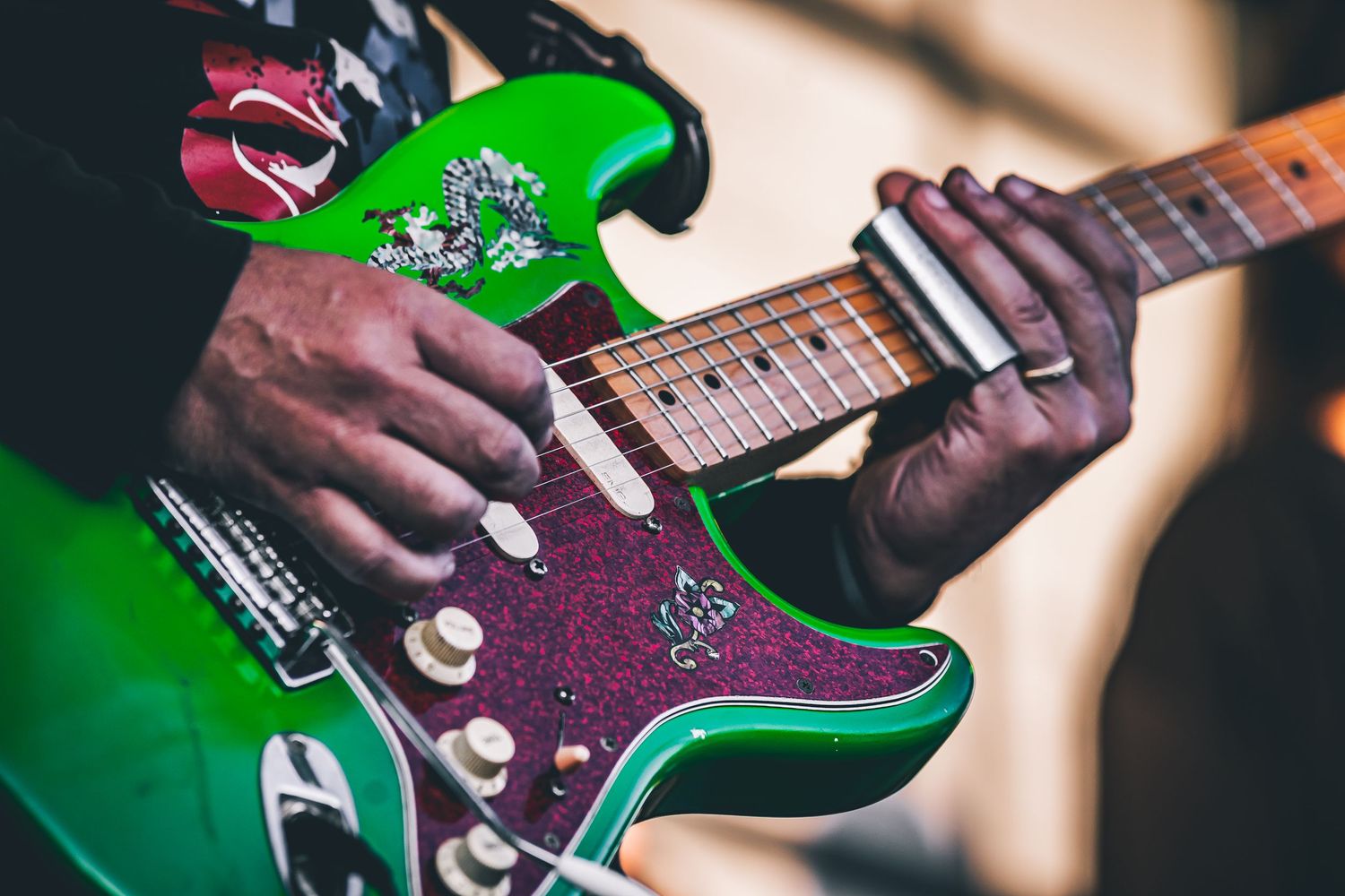 Close up of hands playing bright green electric guitar with purple pickguard.