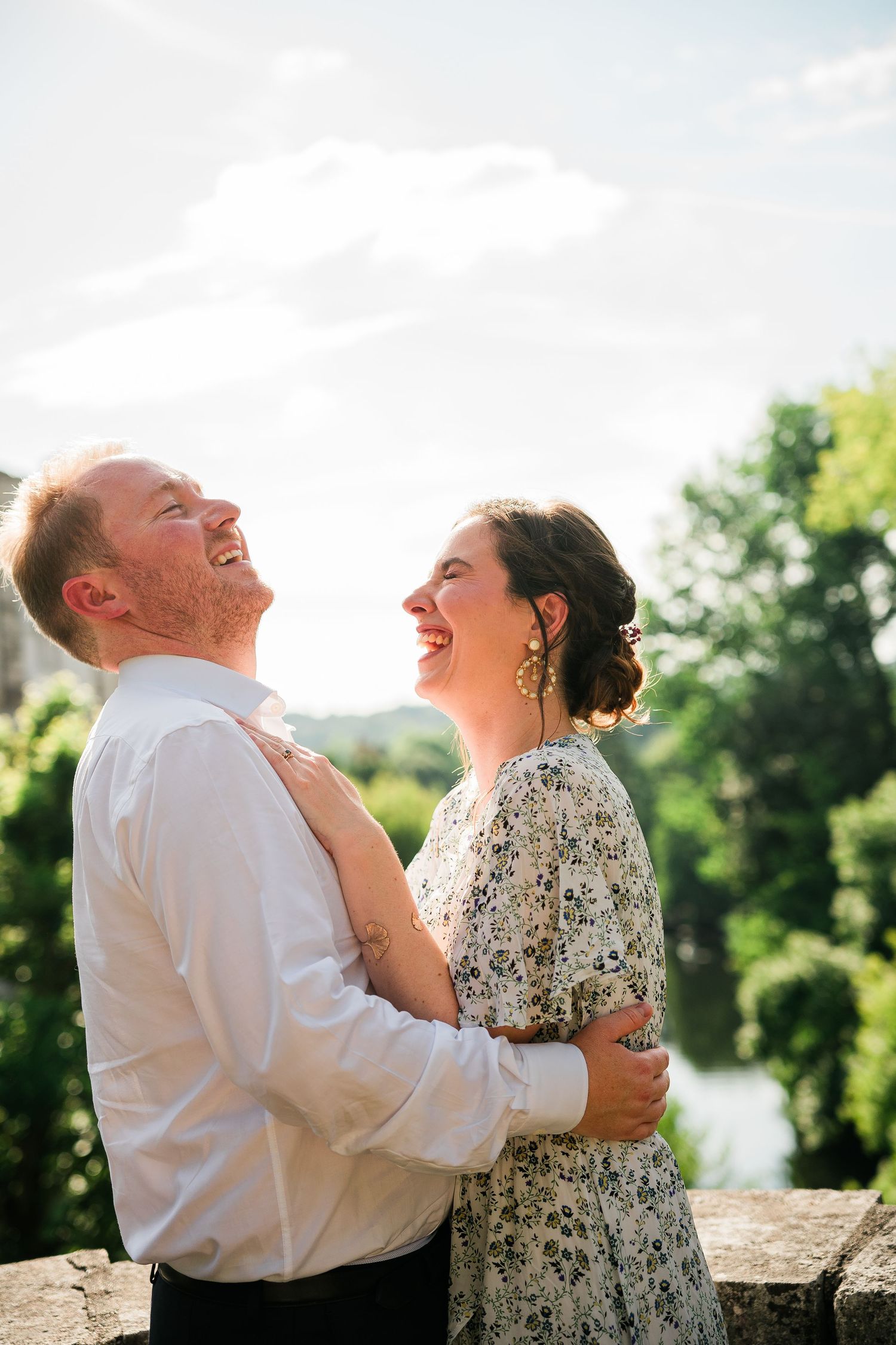 A joyful couple laughing together against a bright summer sky.