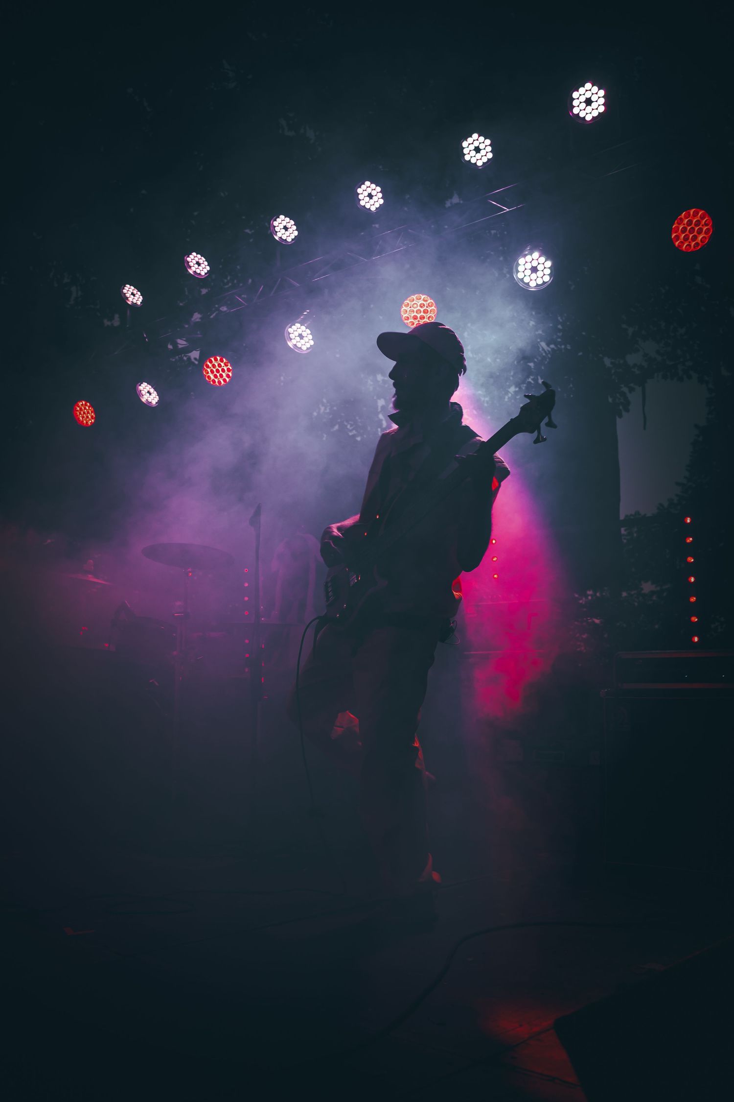 Silhouetted figure performs in atmospheric purple and pink stage lighting with disco ball effects creating a moody ambiance.