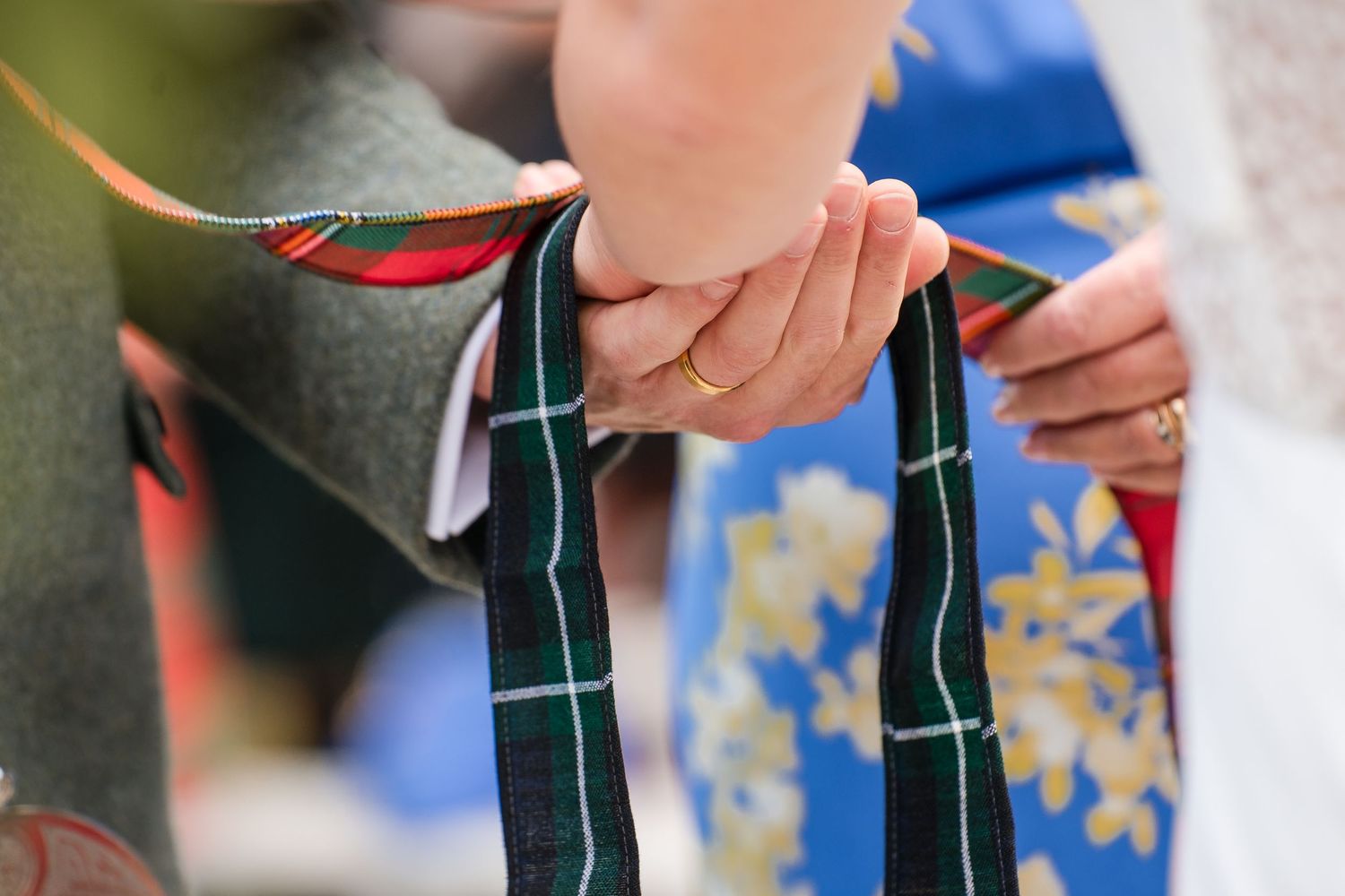 Close-up detail of hands holding a plaid patterned fabric or accessory.