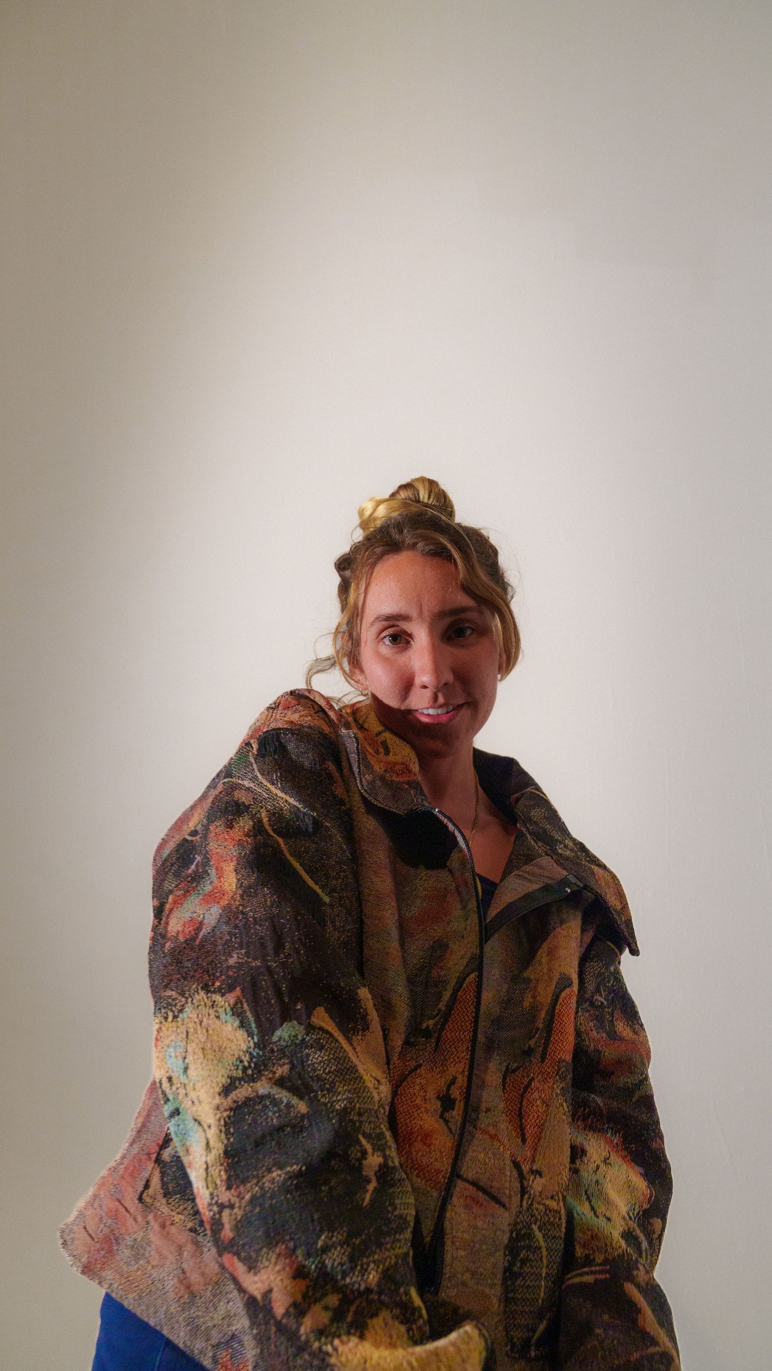 Person wearing a textured brown patterned jacket poses playfully against a white background.