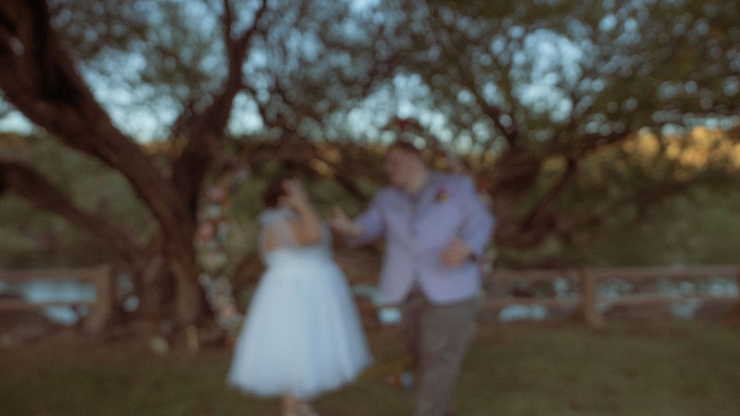 Blurred outdoor wedding scene with natural greenery in background.