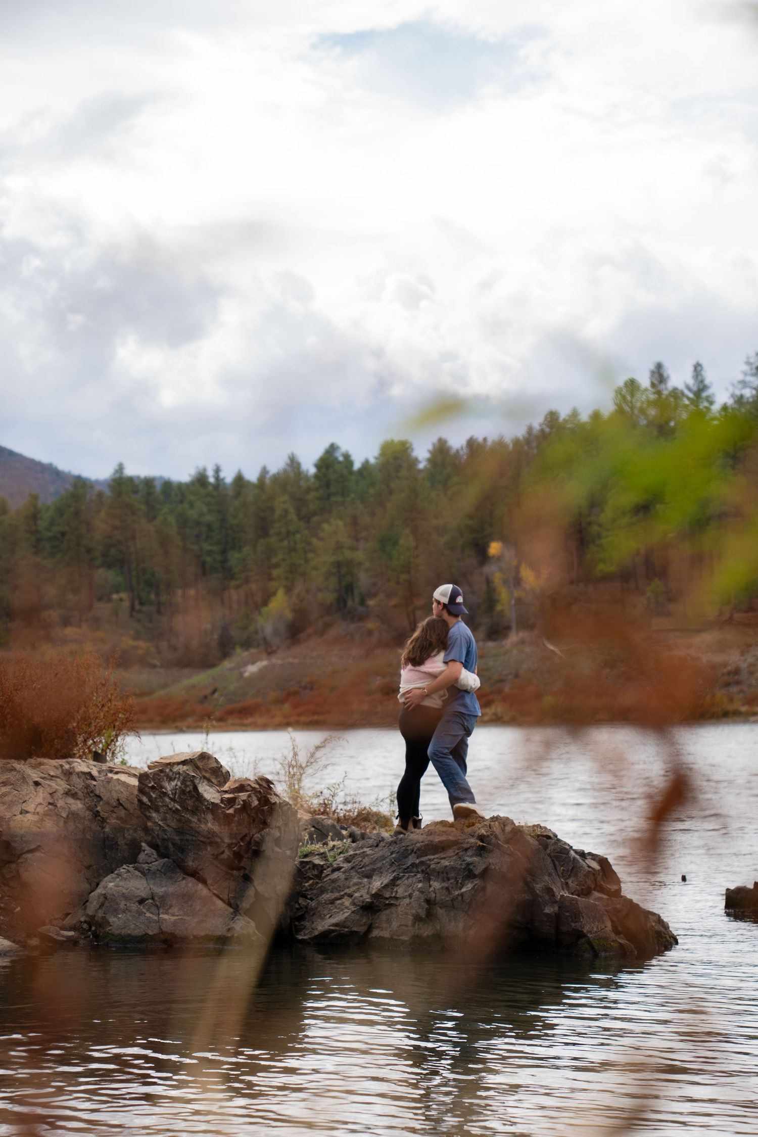 A sequence of shots showing people on a rocky ledge overlooking a serene lake.