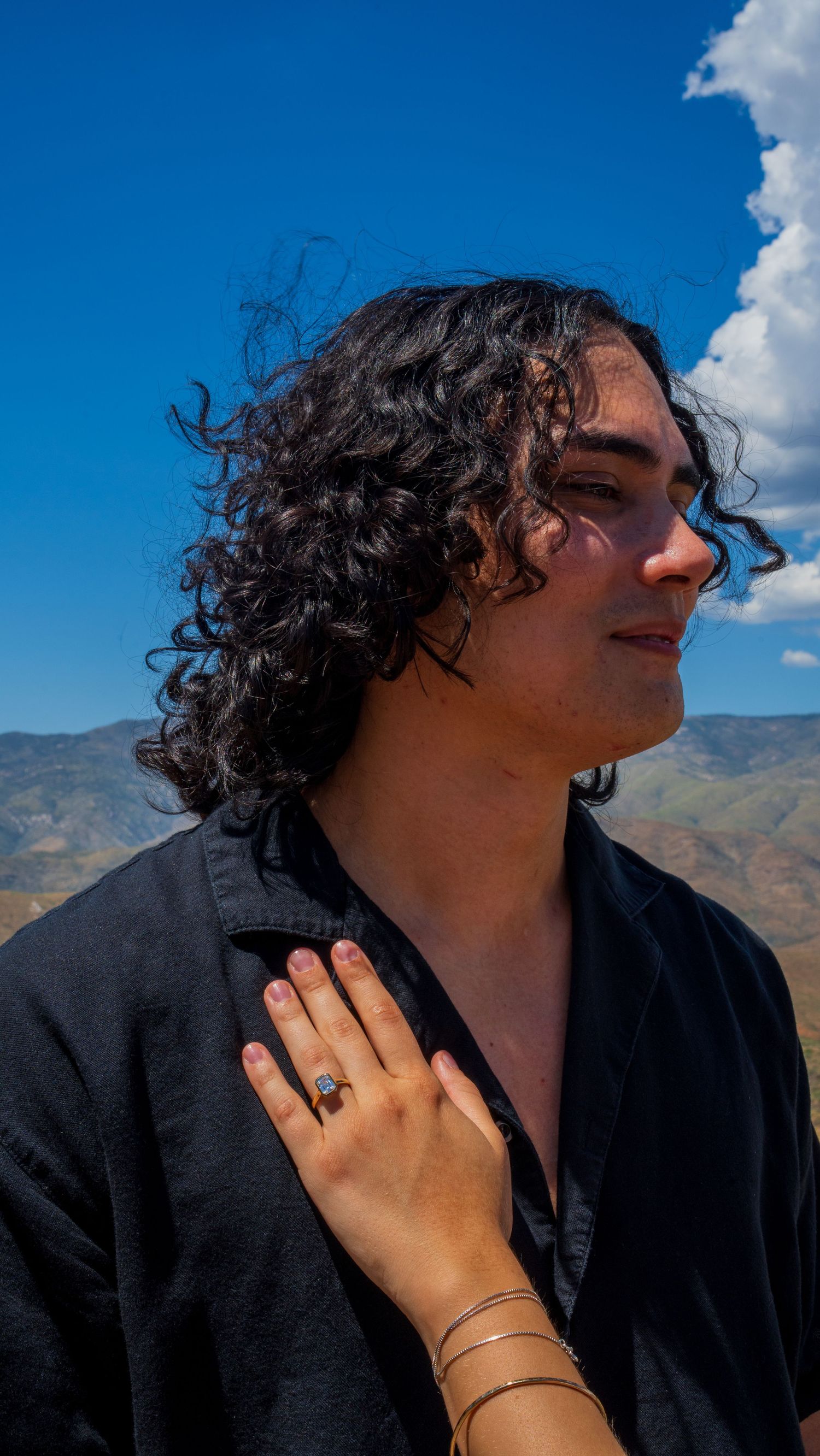 Close-up shots showing hands and jewelry against a bright blue desert sky.