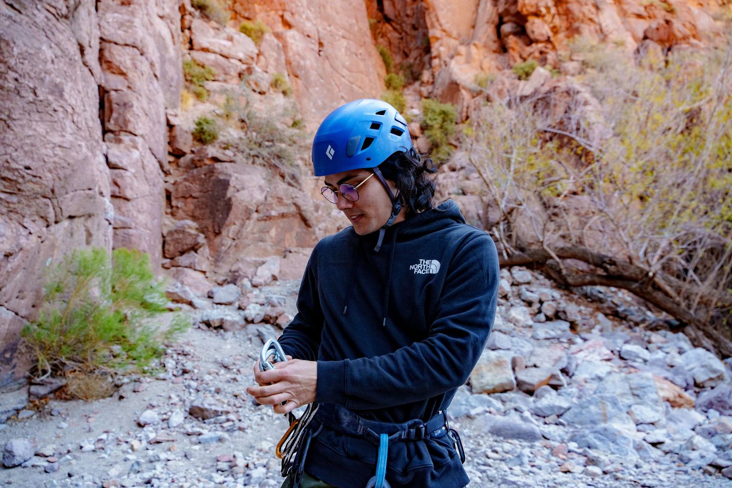 Rock climbers preparing gear at base of towering canyon walls.