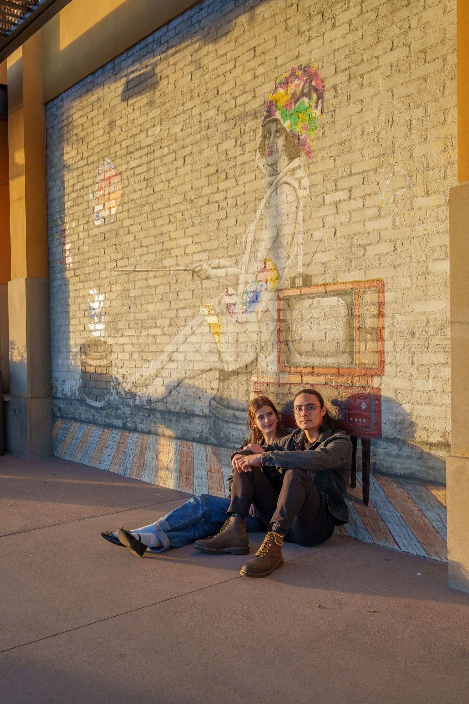 Casual portrait session against brick wall with warm sunset lighting.