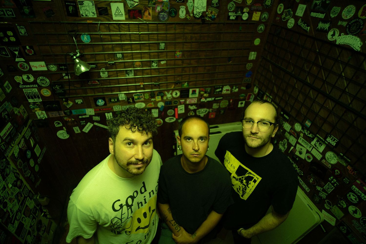 The members of the band Troubled Minds pose inside a bar venue with serious faces under the flash of a neon green light.
