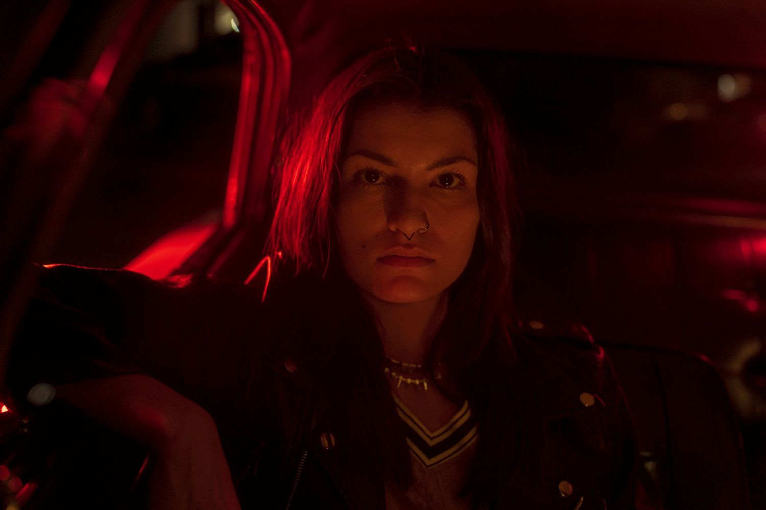 Moody portrait in dark red lighting creating dramatic shadows and atmosphere.
