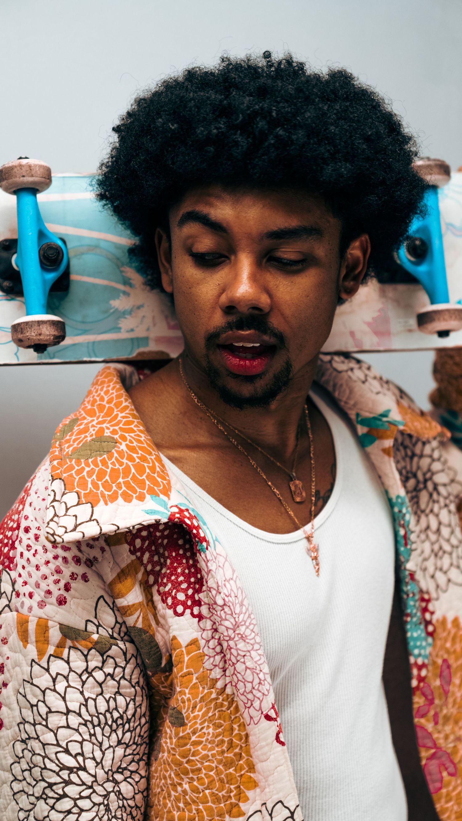 Colorful patterned jacket detail with skateboard in vibrant orange and white design.