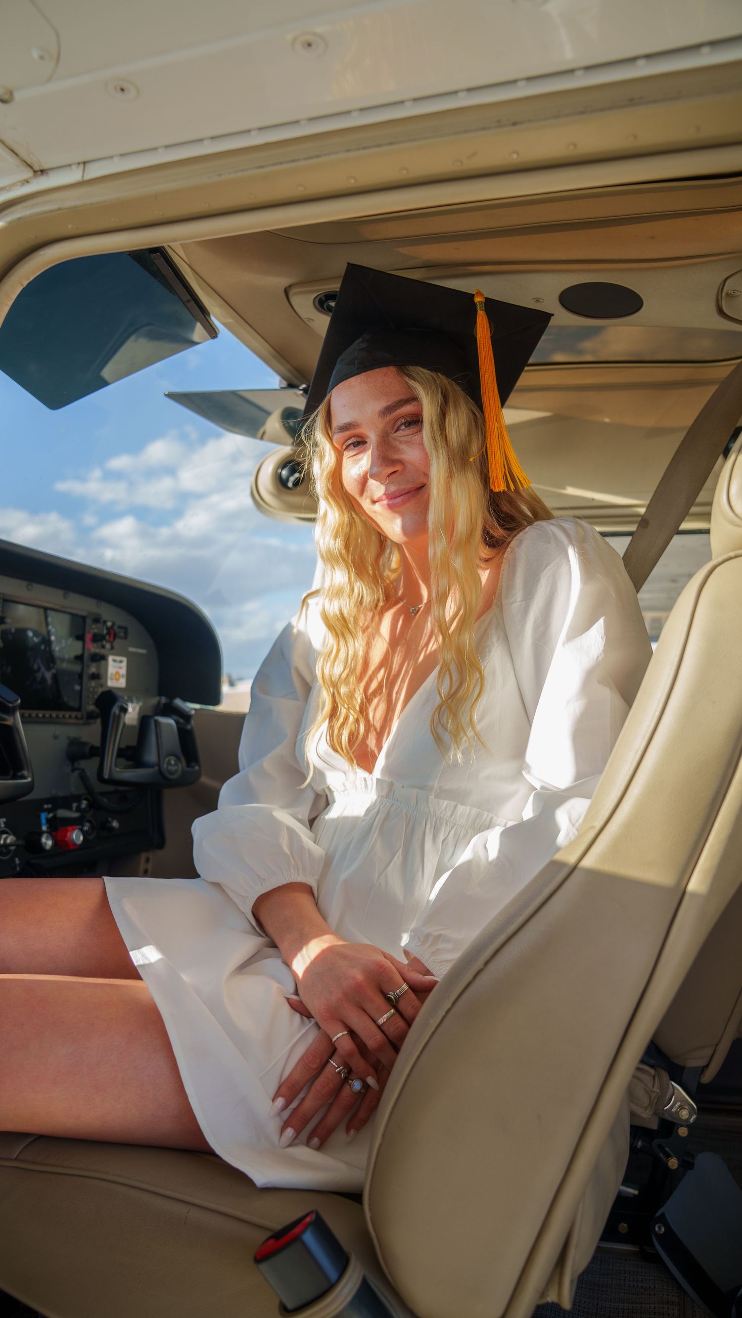 Person in white dress seated in private aircraft interior during daytime flight.