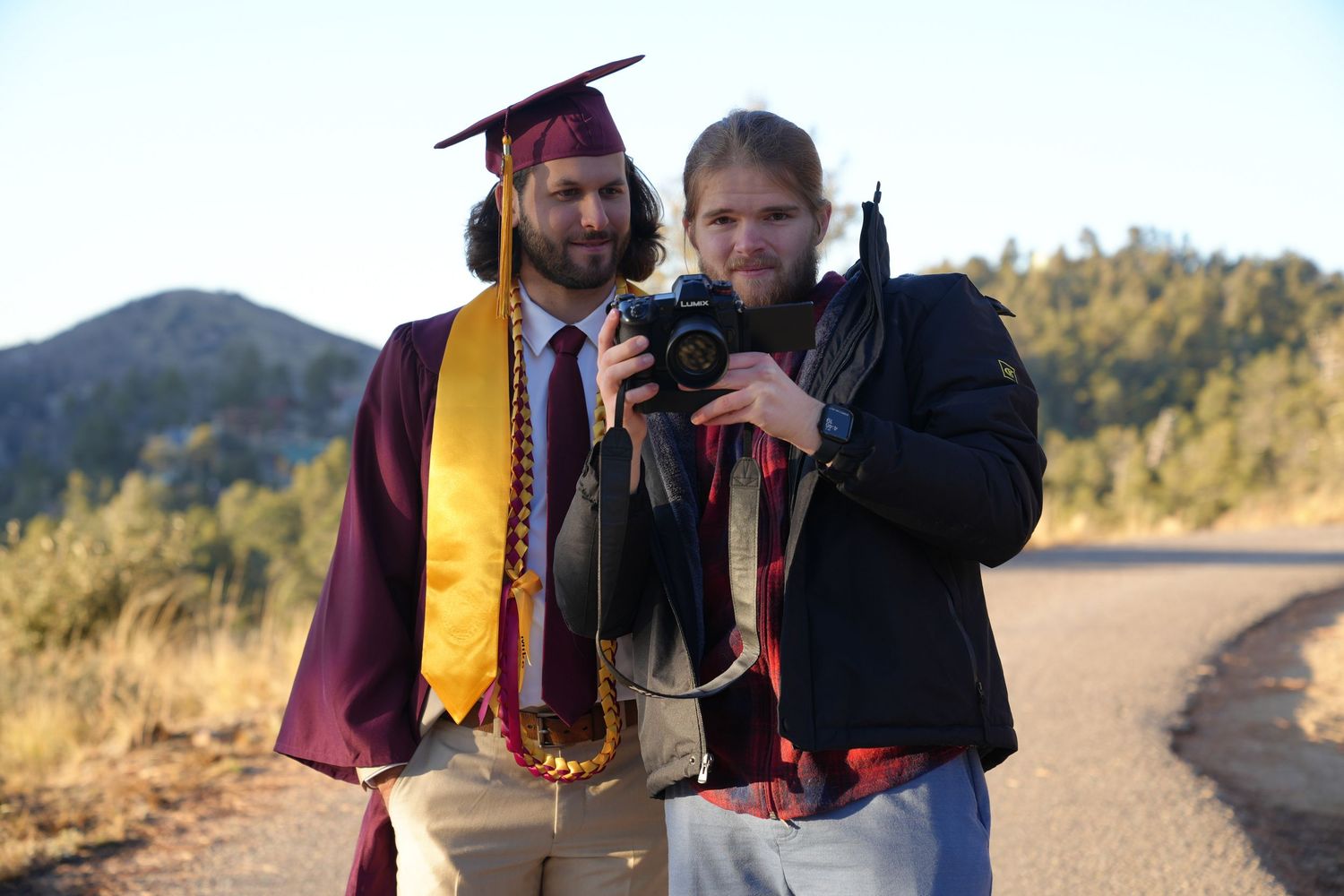 Group of graduates celebrate together outdoors wearing academic regalia.