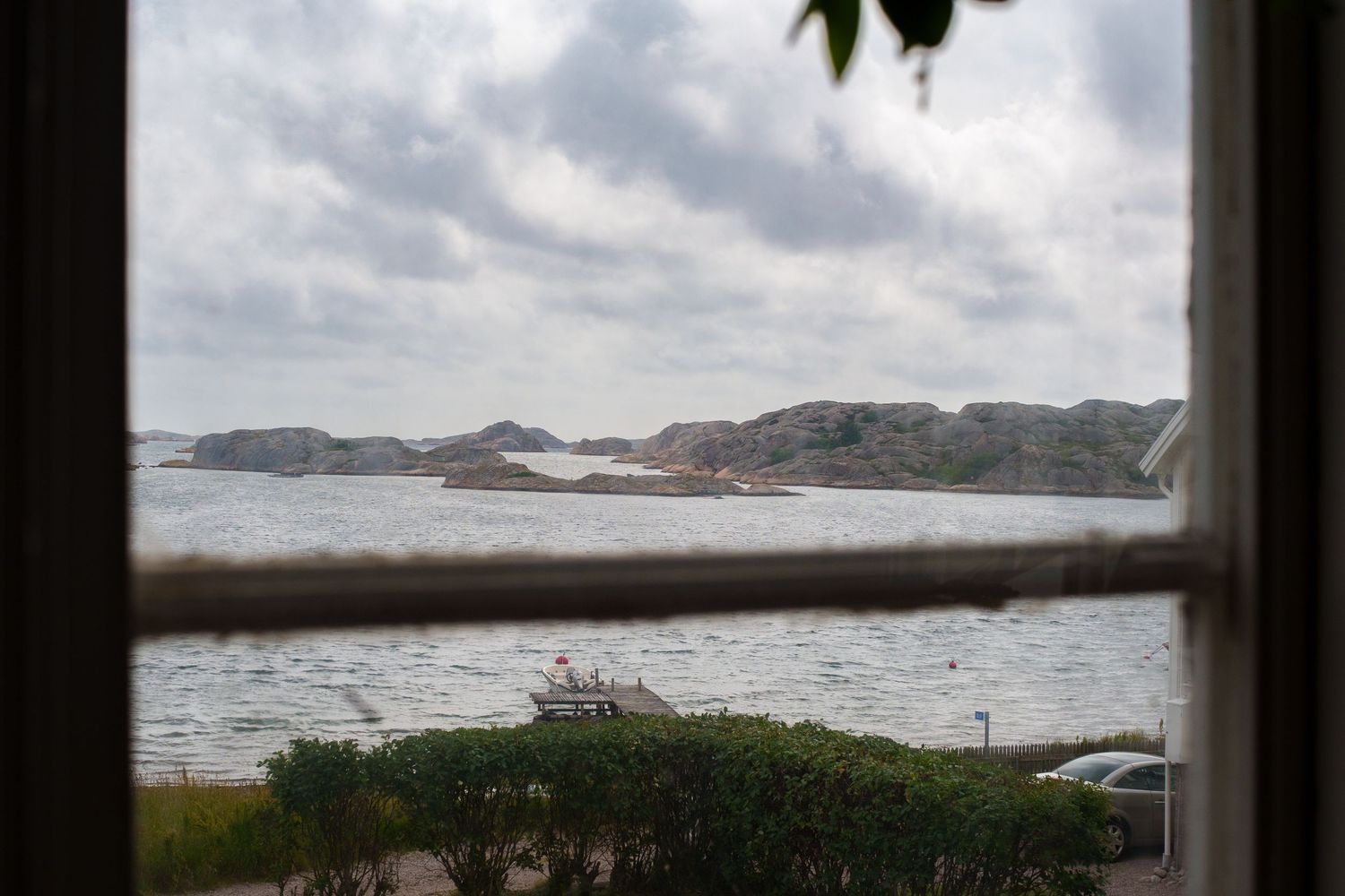 Scenic coastal landscape with rolling hills and cloudy skies viewed through a window frame.