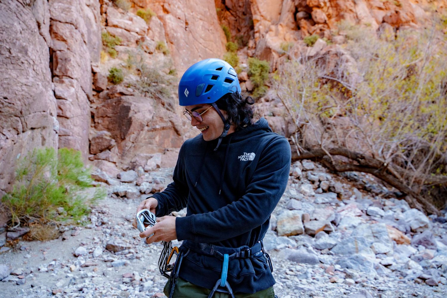 Rock climber exploring rocky canyon terrain while taking photographs.
