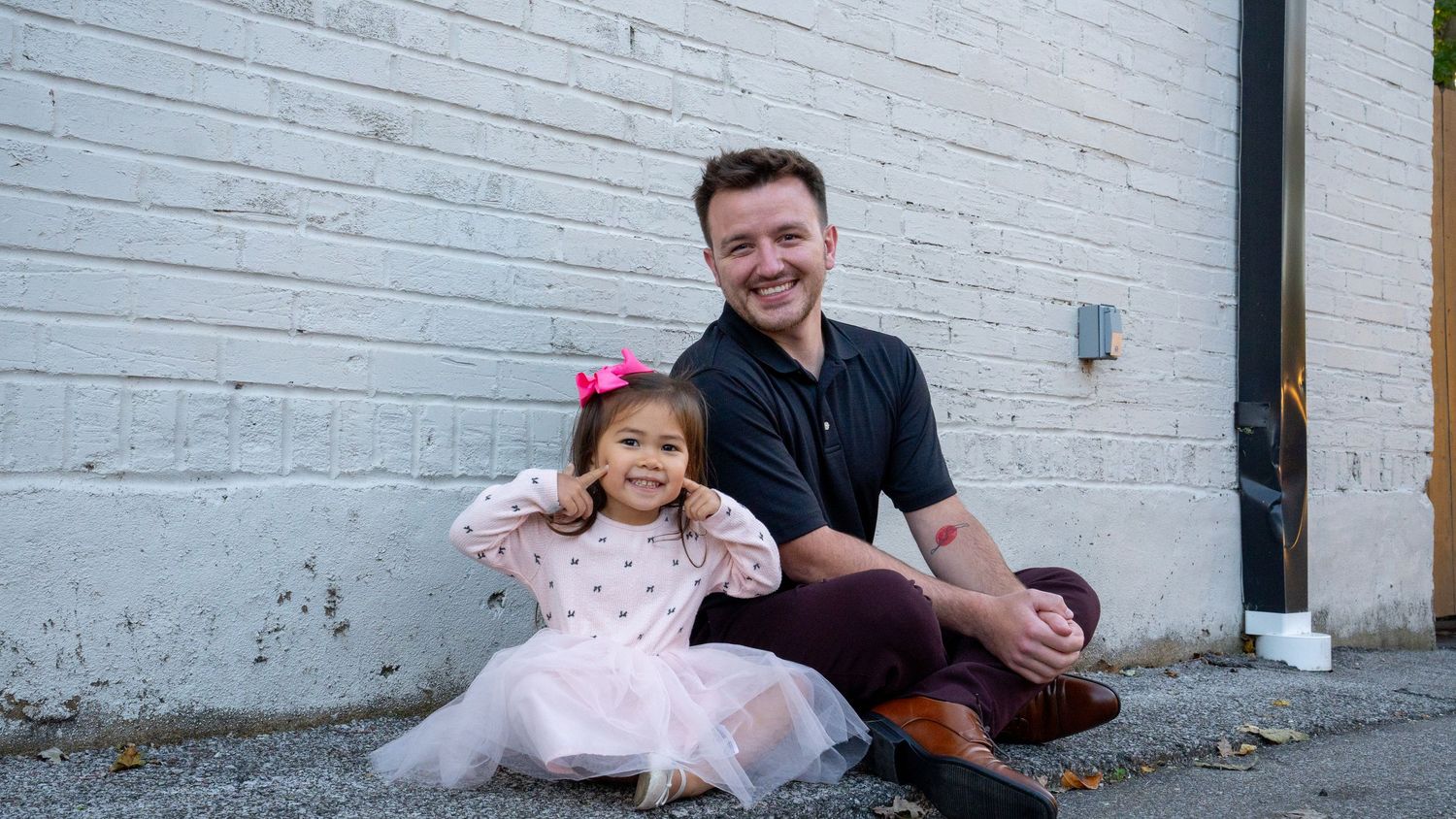 Family portrait session against white brick wall outdoors.