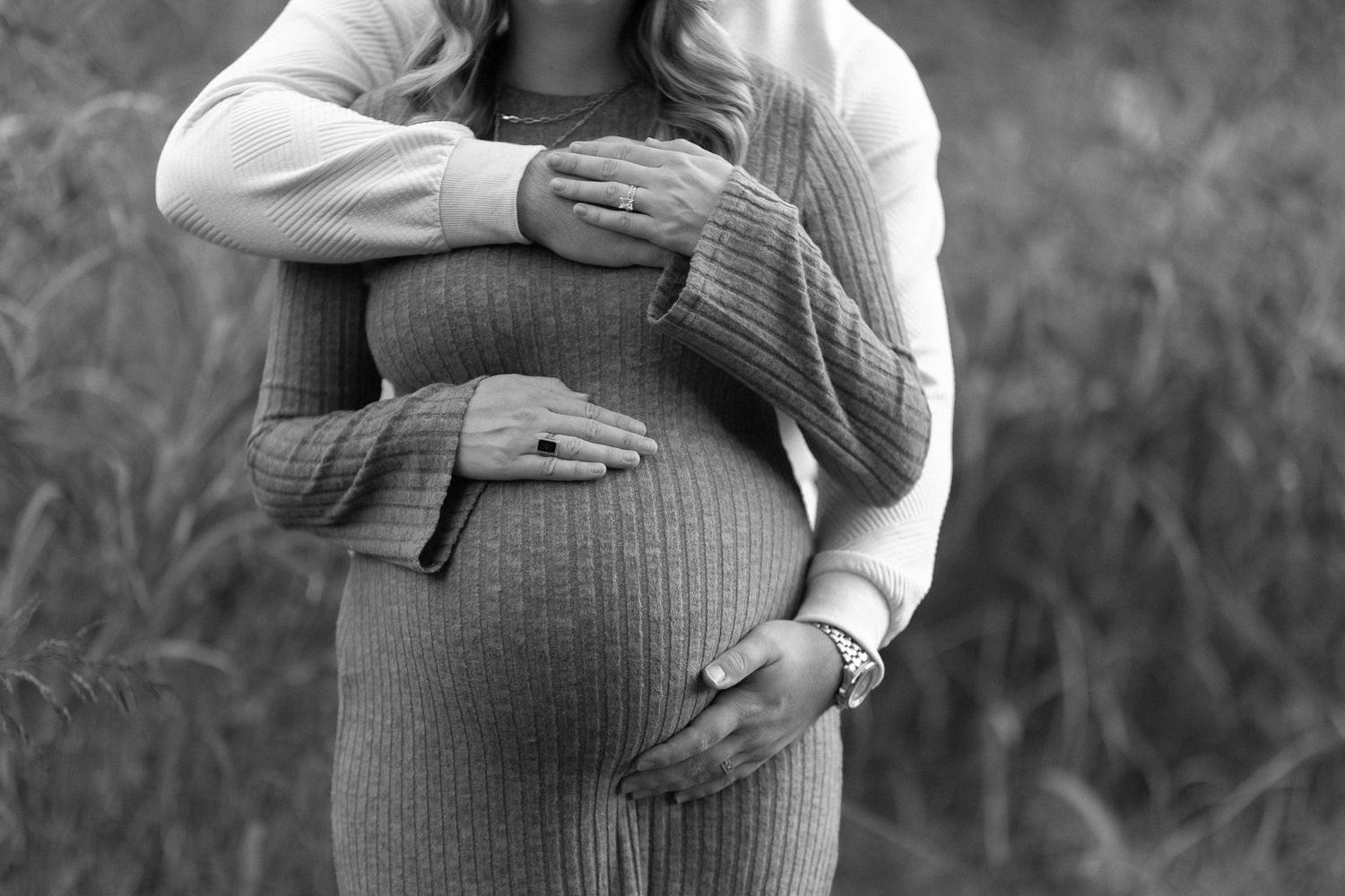 Couple gently wrapping their hands around the woman’s pregnant belly during a maternity photoshoot, capturing tenderness and anticipation.