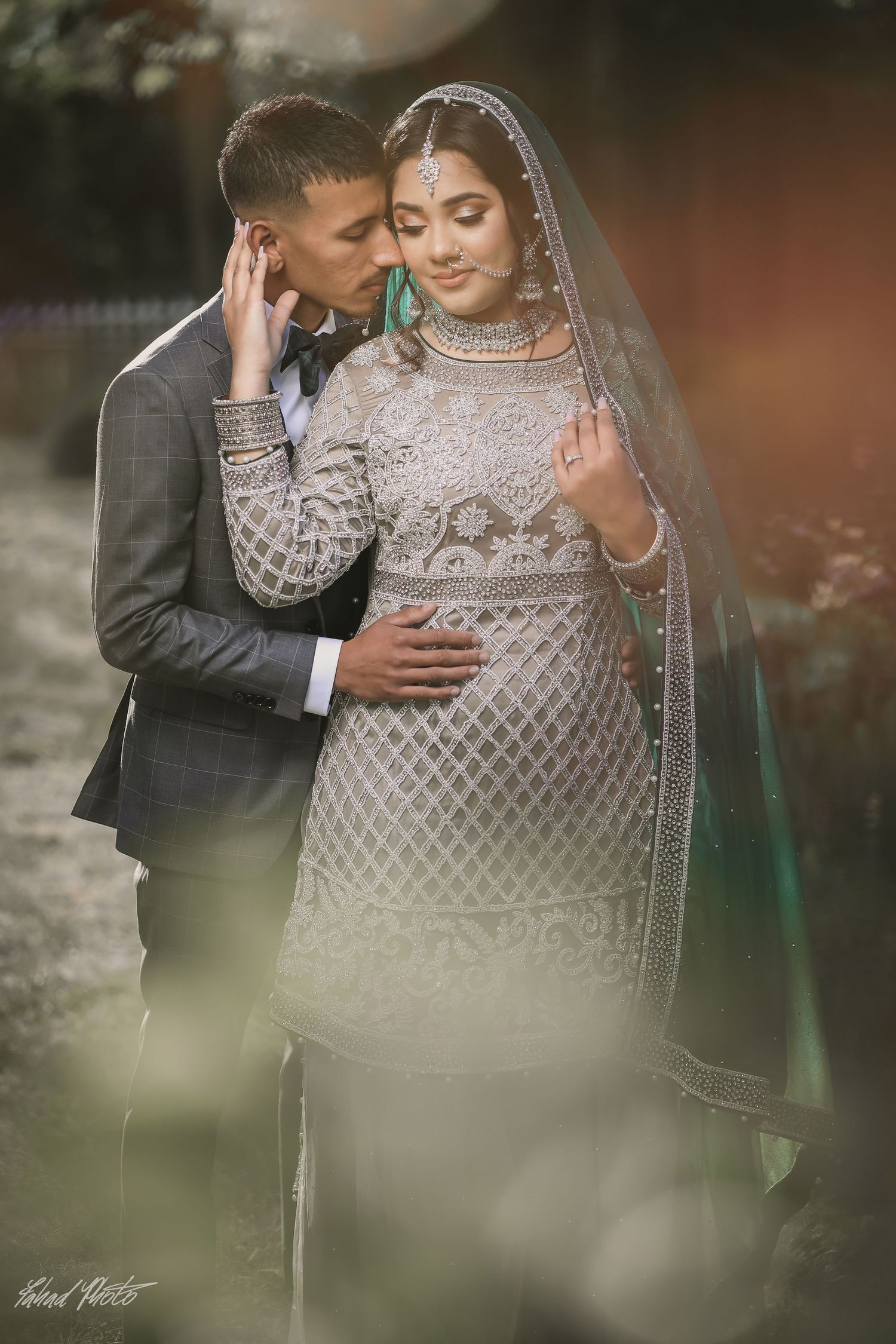 Bride in sheer bridal veil with groom, soft-focus engagement portrait